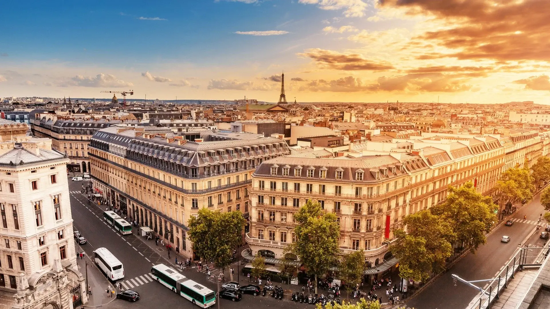 Atmospheric cityscape of Paris at sunset, with the Eiffel Tower on the horizon.