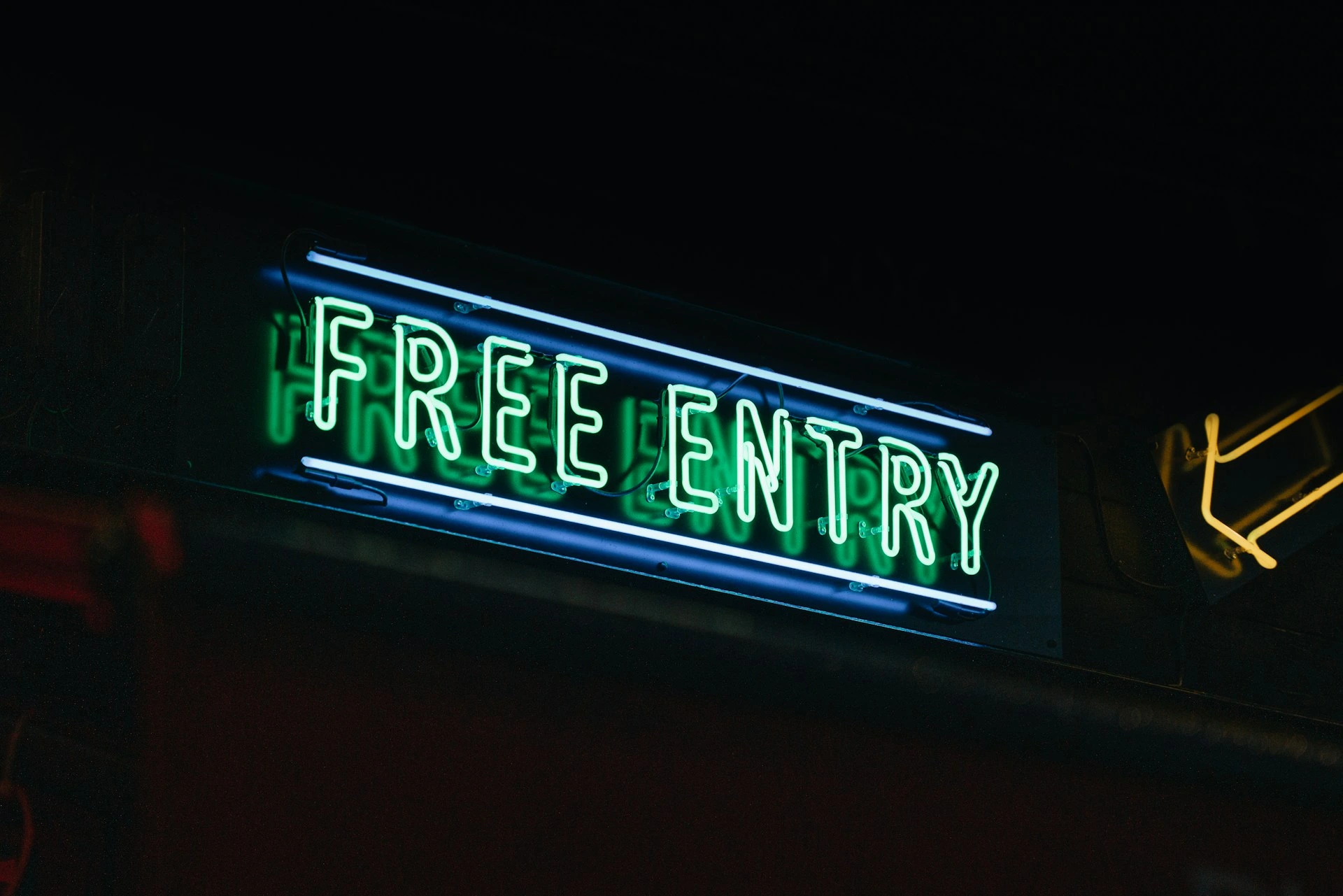 A neon sign with the words "FREE ENTRY" in green and blue, symbolizing free eSIM trials